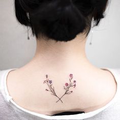 the back of a woman's neck with pink flowers on her left side tattoo