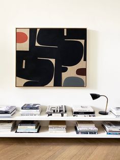 a book shelf with books on it and a painting hanging above the shelves in front of it