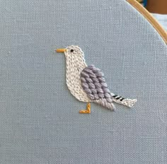 a close up of a bird embroidered on a piece of fabric with scissors in the background