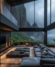 a living room with couches and tables in front of large windows overlooking the mountains