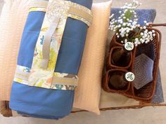 a blue bag sitting on top of a pillow next to a vase filled with flowers