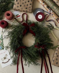 the wreath is surrounded by ribbon, sprigs and other crafting supplies on a table