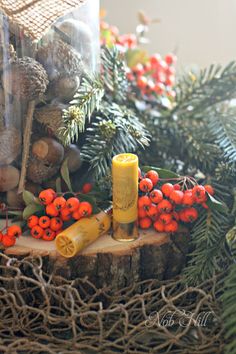 an assortment of christmas decorations including pine cones, berries and a yellow tube on a tree stump