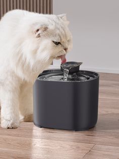 a white cat drinking water from a black fountain with its tongue hanging out and it's face in the water