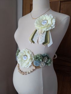 a white mannequin with flowers on it's belt and tags attached to the waist