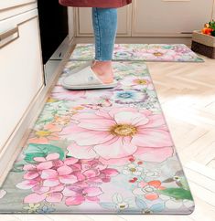 a woman standing on top of a kitchen floor next to a flowered area rug