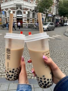 two people holding up cups with drinks in them