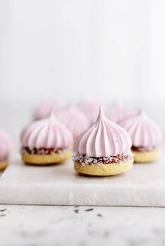 small pink frosted pastries sitting on top of a white counter