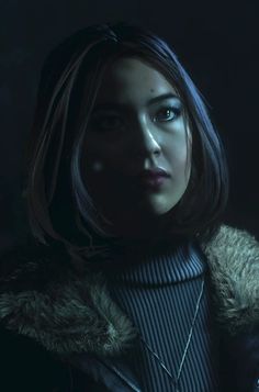 a woman in a dark room wearing a fur coat and looking off into the distance