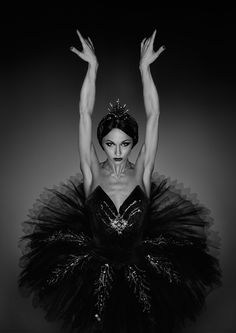 a black and white photo of a woman in a tutu with her hands up