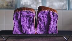 two pieces of bread with purple frosting on them are sitting on a cooling rack