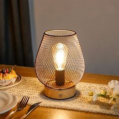 a lit candle sits on a table next to some plates and silver utensils