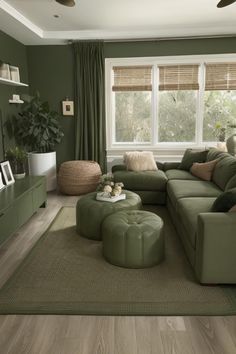 a living room with green walls and wooden flooring, large sectional couch in front of the window