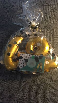 gold foil balloons in the shape of numbers are wrapped in plastic cellophane and have black polka dots on them