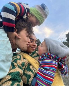 a group of people standing next to each other with one child on his shoulders and the other holding an adult's head