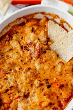 a tortilla dip in a white bowl with a cracker on the side