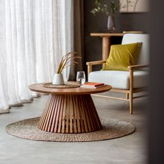 a living room with a chair, table and vase on the floor in front of a window