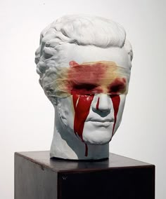 a white head with red and yellow paint on it's face is shown in front of a white wall