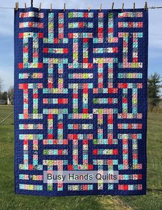 a quilt hanging from a clothes line on a clothes line with the words busy hands quilts written across it