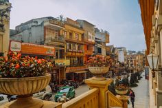 a city street filled with lots of tall buildings and flowers on the balconies