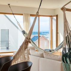 a living room filled with furniture and a hammock hanging from the ceiling next to a window