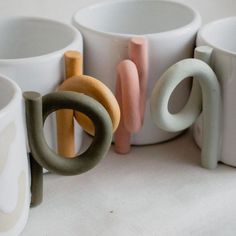 several different colored cups sitting next to each other on a white tablecloth covered surface