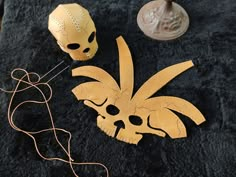 two masks sitting on top of a black surface next to a string and some other items