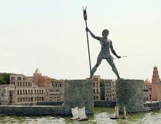 a statue of a man holding a spear on top of a bridge