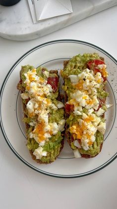 two open faced sandwiches on a plate with cheese and tomato toppings next to a computer keyboard