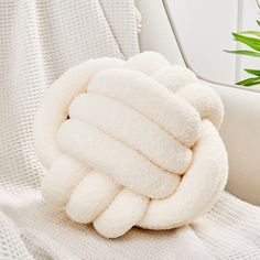 a pile of white towels sitting on top of a couch next to a potted plant