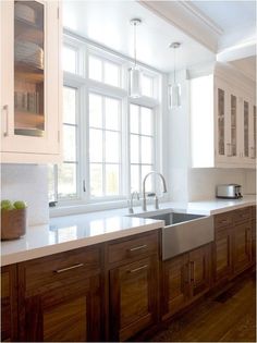 a kitchen with wooden cabinets and white counter tops next to a window filled with fruit