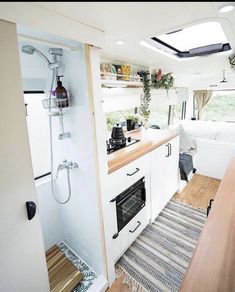 the interior of a camper with wood flooring and white walls, including an oven