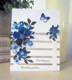 a birthday card with blue flowers and butterflies on it, sitting next to some books