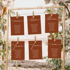 the seating chart for this wedding is hanging on a wooden frame with flowers and greenery