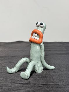 a ceramic figurine sitting on top of a black cloth covered floor next to a white wall