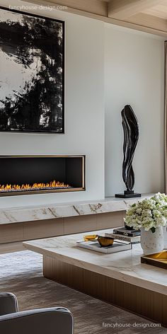 a modern living room with a fireplace in the center and art on the wall behind it