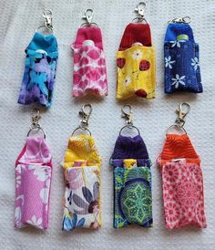 six small purses are lined up on a white surface with keychains attached to them