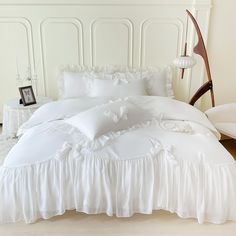 a white bed with ruffled sheets and pillows