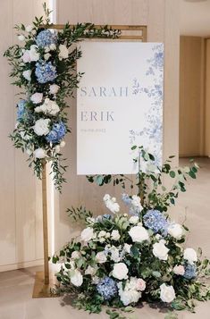 flowers and greenery are arranged in front of a sign