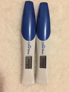 two blue and white toothbrushes sitting next to each other on top of a carpet