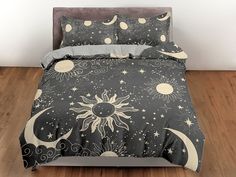 a bed covered in a black and white comforter with sun and moon designs on it