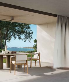 an outdoor dining area with table and chairs overlooking the ocean on a sunny day,