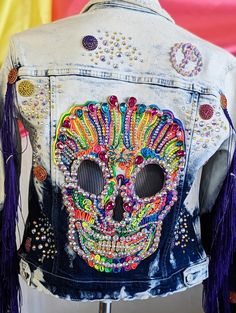 a jacket with a skull painted on the back and tassels attached to it