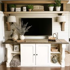 a flat screen tv sitting on top of a wooden shelf next to a white cabinet