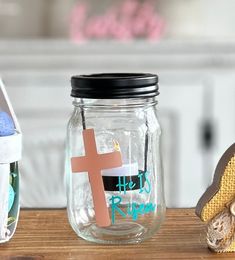 there is a glass jar with a cross on it and other items in the background