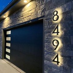 an illuminated house number sign on the side of a garage door with lights above it