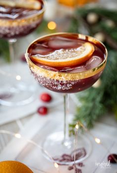 two glasses filled with chocolate and oranges on a table next to an orange slice