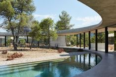 an empty pool in front of a large building with glass walls and trees on the other side