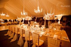 the tables and chairs are set up for a formal function with chandeliers hanging from the ceiling