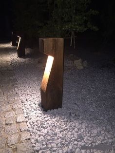 a light shines in between two wooden posts on a cobblestone path at night